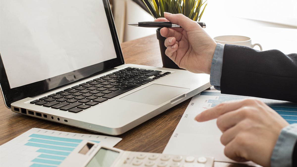 Empresário com notebook e calculadora sobre a mesa, avaliando o orçamento de um site
