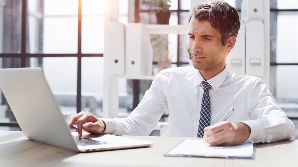 Profissional de camisa branca olhando pensativo para o monitor no escritório
